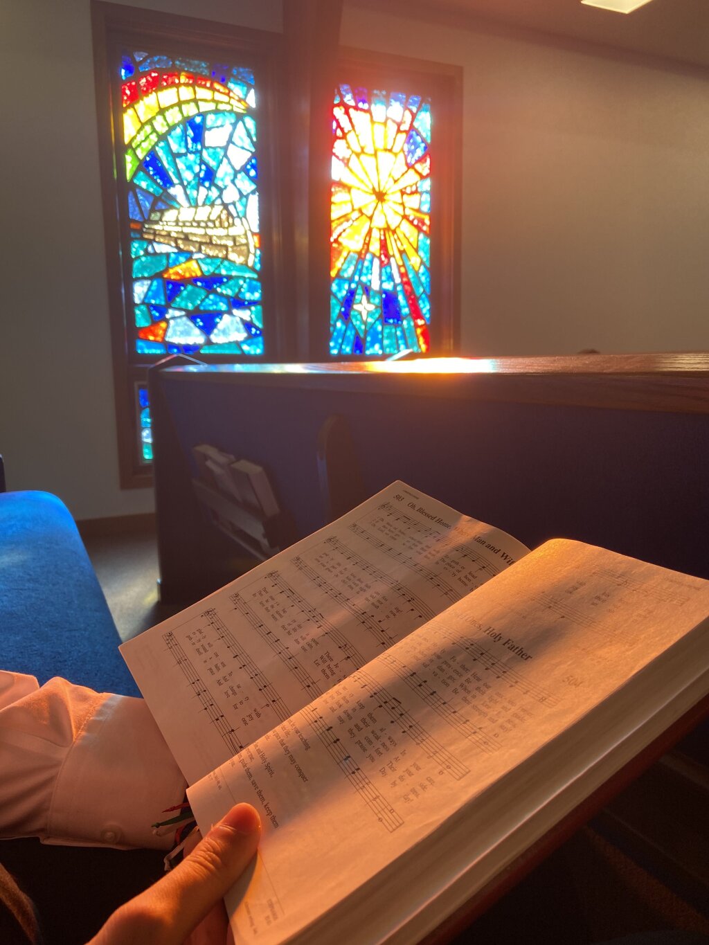Open hymnal with light streaming through stained glass windows.